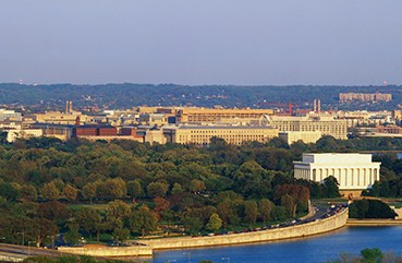 aerial view of Washington, DC. The Potomac River runs through the center with the Key Bridge at right at sunset.