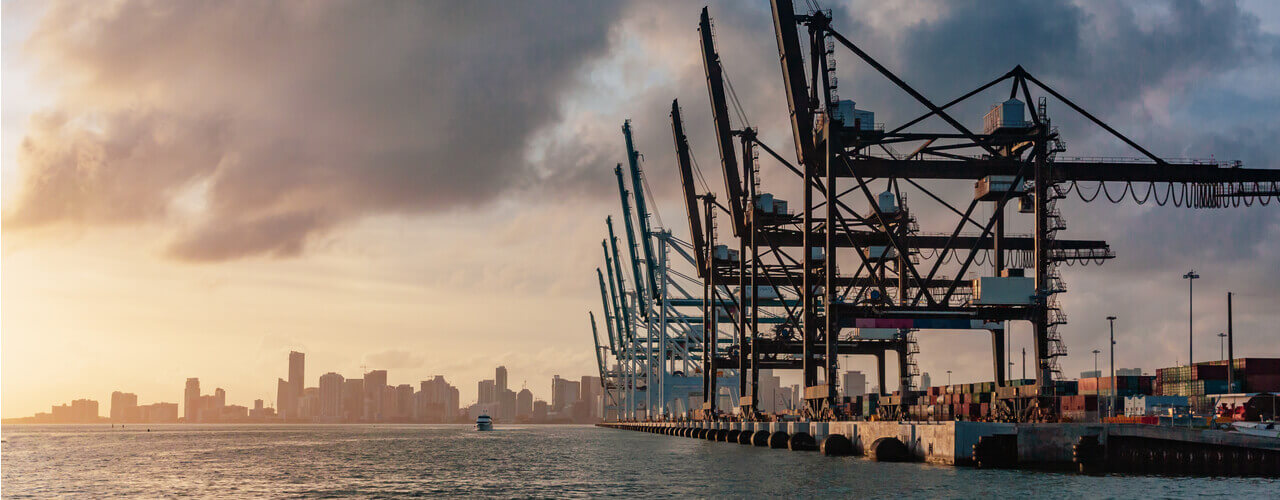 Aerial view of cranes in the Port of Miami with the Miami skyline in the background