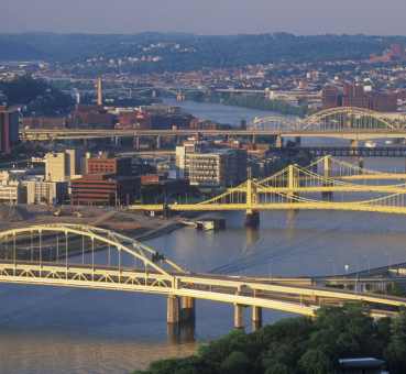 aerial view of Pittsburgh office buildings on the shore of the Allegheny river and of several of the city's bridges across the river.