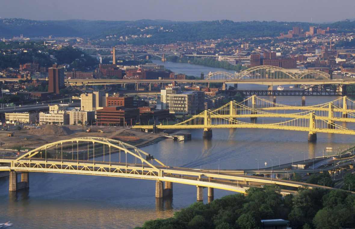 aerial view of Pittsburgh office buildings on the shore of the Allegheny river and of several of the city's bridges across the river.