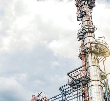 Towers of an industrial plant with sky and clouds as background