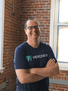 Alan Mackay, CEO of Werqwise Coworking, standing with arms crossed in front of a brick wall