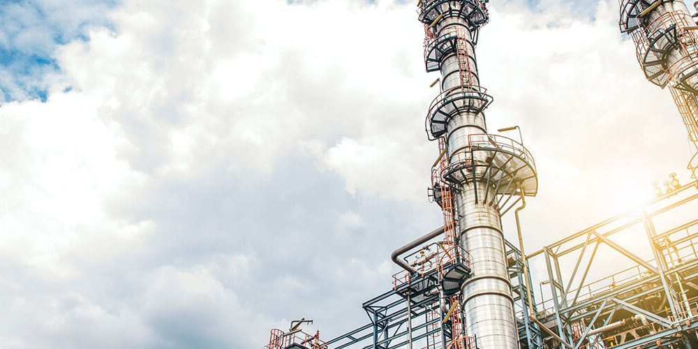 Towers of an industrial plant with sky and clouds as background