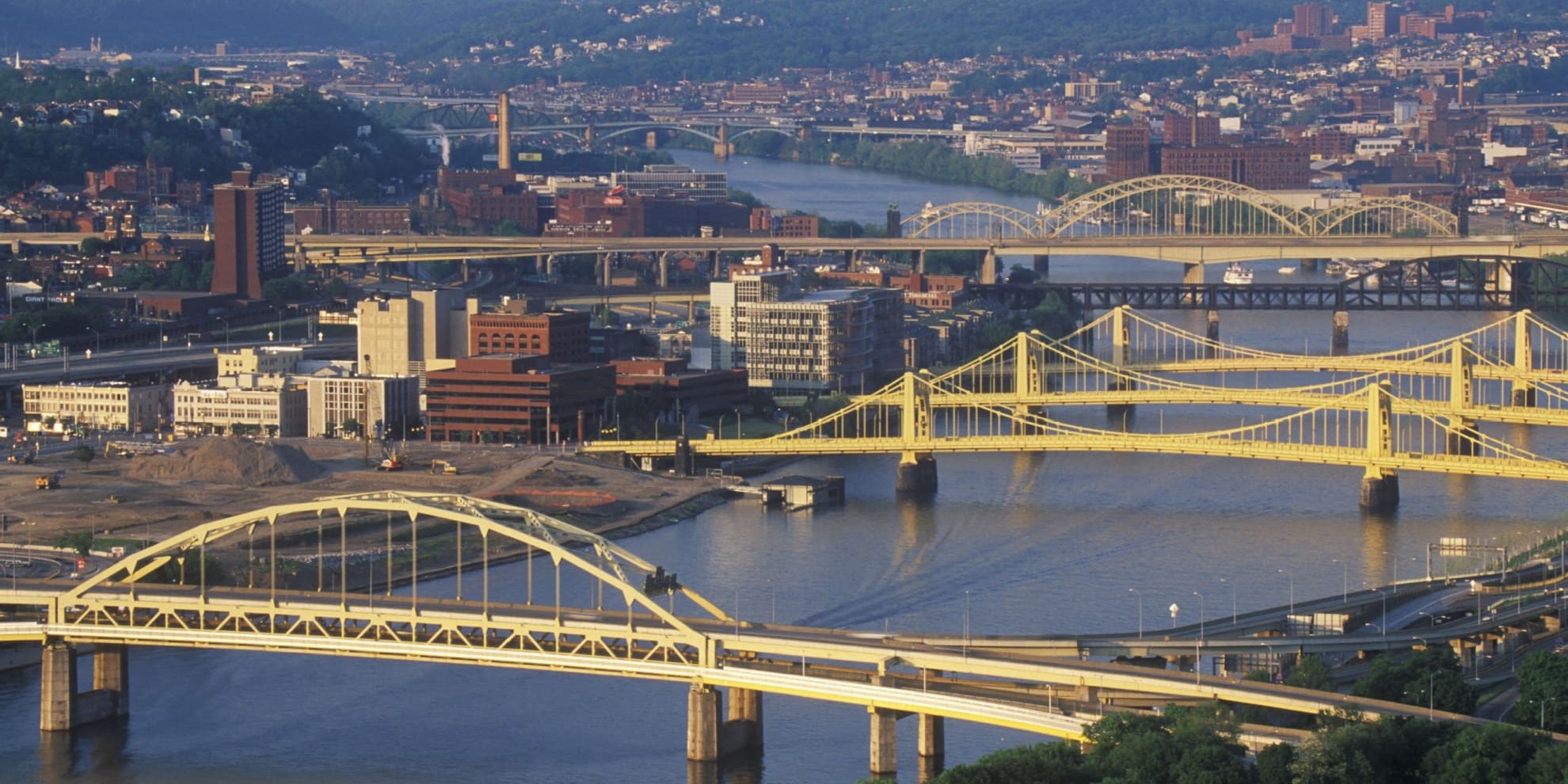 aerial view of Pittsburgh office buildings on the shore of the Allegheny river and of several of the city's bridges across the river.
