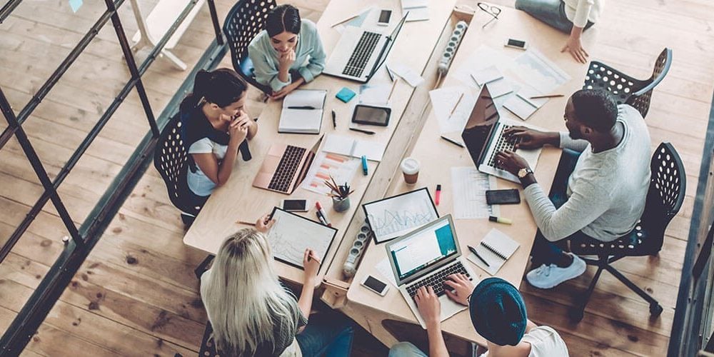 Multiracial group of people sitting at a table in a coworking hub