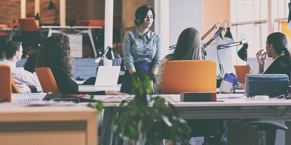 Several people sitting and standing in an office