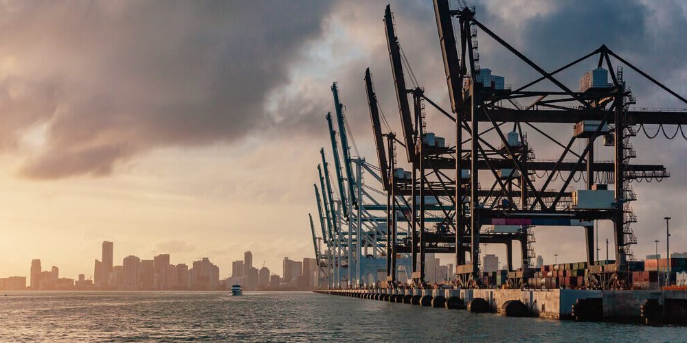 Aerial view of cranes in the Port of Miami with the Miami skyline in the background
