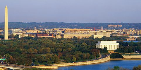 aerial view of Washington, DC. The Potomac River runs through the center with the Key Bridge at right at sunset.