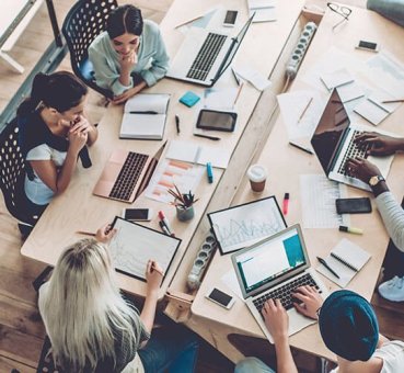 Multiracial group of people sitting at a table in a coworking hub