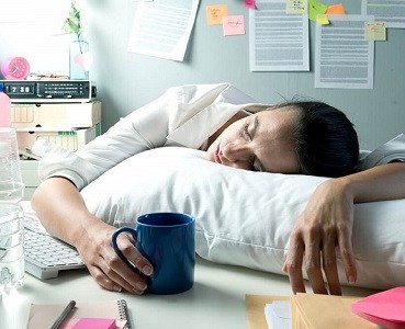 Image of female employee napping at her desk due to exhaustion