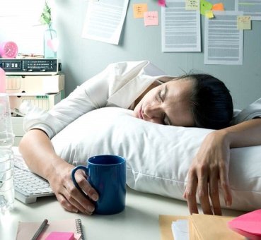 Image of female employee napping at her desk due to exhaustion