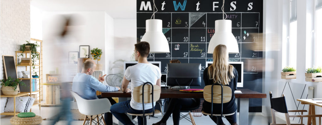 Several people sitting with their back towards the camera in a coworking office