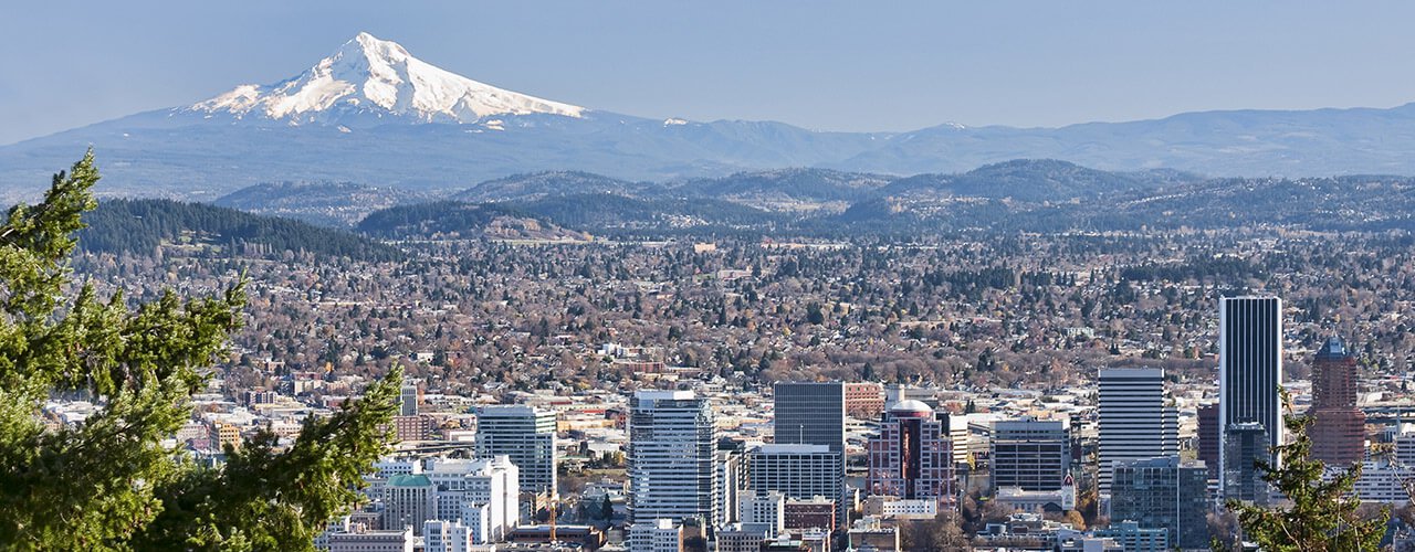 A wide shot of the skyline of Portland, OR with Mount Hood in the background